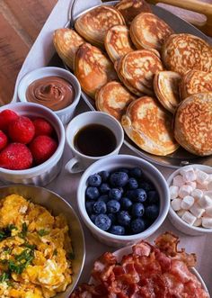 the breakfast is ready to be eaten on the table with fruit, pancakes and other foods