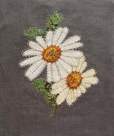 two white daisies with green leaves on a gray background, embroidered onto the fabric