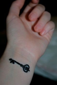 a small wrist tattoo with a key on it