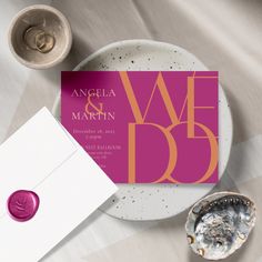 the wedding stationery is displayed next to an envelope and seashell