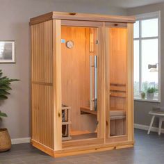 a wooden sauna in a living room next to a potted plant