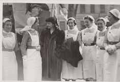 black and white photograph of women in aprons standing next to each other with one man