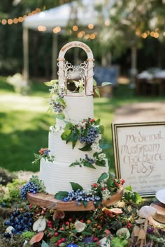 a wedding cake with flowers and greenery on the top is surrounded by other decorations