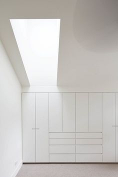 an empty room with white cabinets and skylight