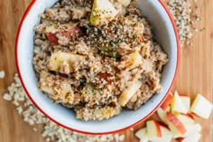 a bowl filled with oatmeal and apples on top of a wooden table