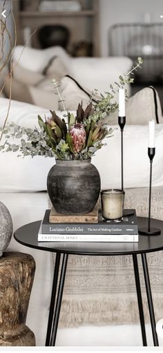 a table with flowers and candles on top of it next to a white couch in a living room