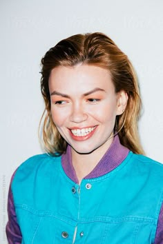 a woman smiling and wearing a blue jacket