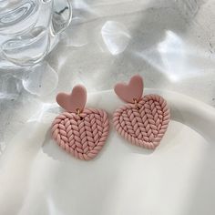 two heart shaped pink earrings on a white plate