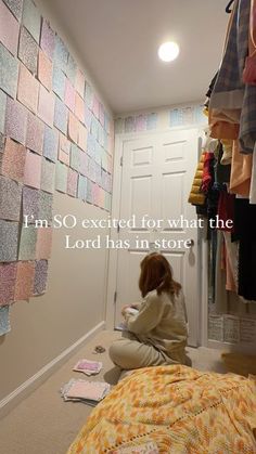 a woman sitting on the floor in front of a closet with clothes hanging up to dry