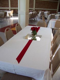 the table is set with white linens and red ribbon