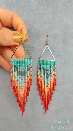 a pair of earrings with beads hanging from it's end, in the shape of triangles