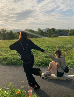 two people sitting on the ground with skateboards in front of them and one person standing