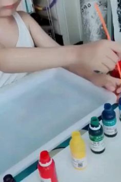 a young boy is painting with watercolors on the table in front of him