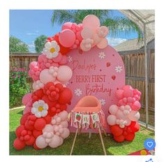 a pink and red birthday party with balloons on the ground, flowers in the center