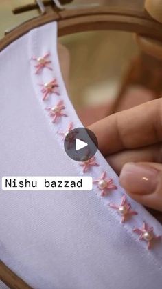 someone is stitching something with pink flowers on it