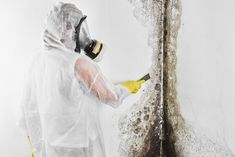 a man in a protective suit spray painting a tree with yellow and white paint on it