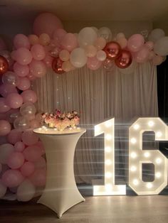 a table topped with a cake next to a giant number 16 sign and some balloons