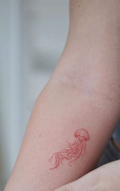 a red inked jellyfish tattoo on the left arm and right arm is shown