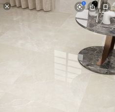 a bathroom with marble flooring and white walls, along with a round glass table