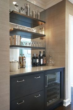 an empty bar with bottles and glasses on the top shelf, next to a wine glass cabinet