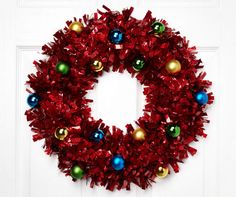 a red christmas wreath with ornaments hanging on the front door's white paneled door