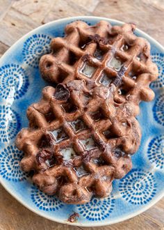 a blue plate topped with waffles covered in syrup