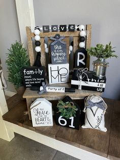 a wooden shelf filled with assorted items on top of a table next to a potted plant