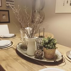 a dining table set with plates, bowls and vases on it's centerpiece