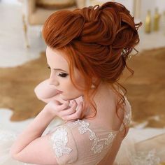 a woman with red hair is sitting on the floor wearing a wedding dress and holding her hand near her face