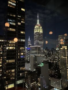 the empire building is lit up at night in new york city, with other skyscrapers visible