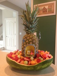 a large bowl filled with lots of fruit on top of a wooden table next to a doorway