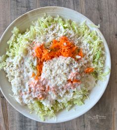 a white bowl filled with coleslaw and carrots on top of a wooden table