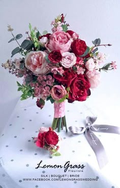 a bouquet of pink and red flowers sitting on top of a white tablecloth covered box