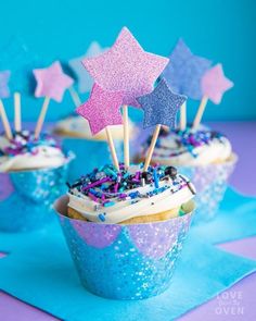 cupcakes decorated with stars and sprinkles on top of blue paper