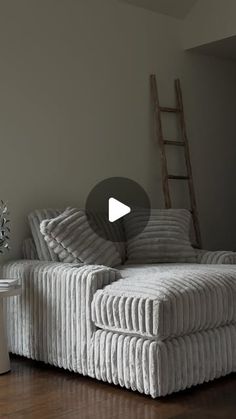 a white couch sitting on top of a hard wood floor next to a tall wooden ladder