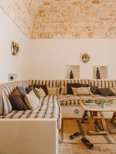 a living room with couches, tables and other items on the floor in front of a brick wall