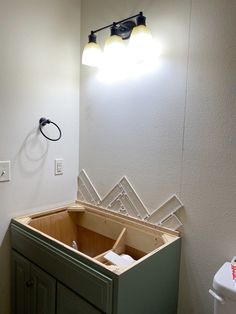 a bathroom with a sink, mirror and light on the wall next to toilet paper dispenser