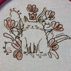 a cross - stitch pattern with a cat and flowers on the bottom half of it