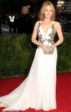 a woman in a white dress standing on a red carpet