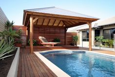 a small pool with a wooden deck next to it and a covered patio area in the background