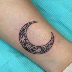 a small crescent tattoo on the wrist with flowers and leaves around it in black ink