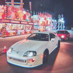 a white car driving down a street next to carnival rides