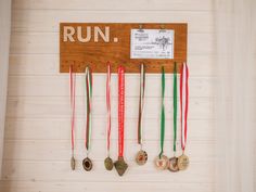 several medals are hanging on the wall in front of a sign that says, run