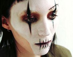 a woman with black makeup and white make - up on her face is looking at the camera