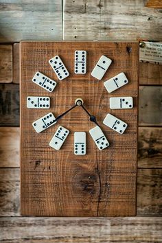 a clock made out of dominos sitting on top of a wooden board