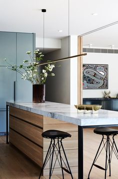 a kitchen island with stools next to it and flowers in a vase on the counter