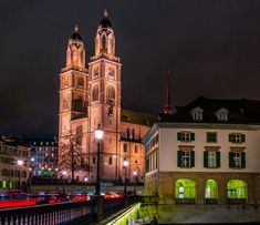 a large cathedral lit up at night with traffic passing by