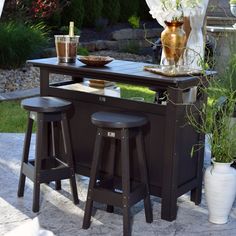 an outdoor bar with stools next to potted plants and flowers on the table