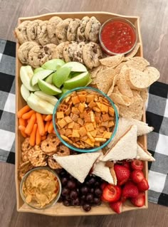 a wooden tray filled with fruit, crackers and veggies