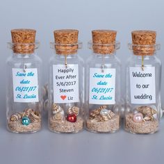 four small glass bottles filled with sand and seashells, labeled happily after 5 / 7 / 2011